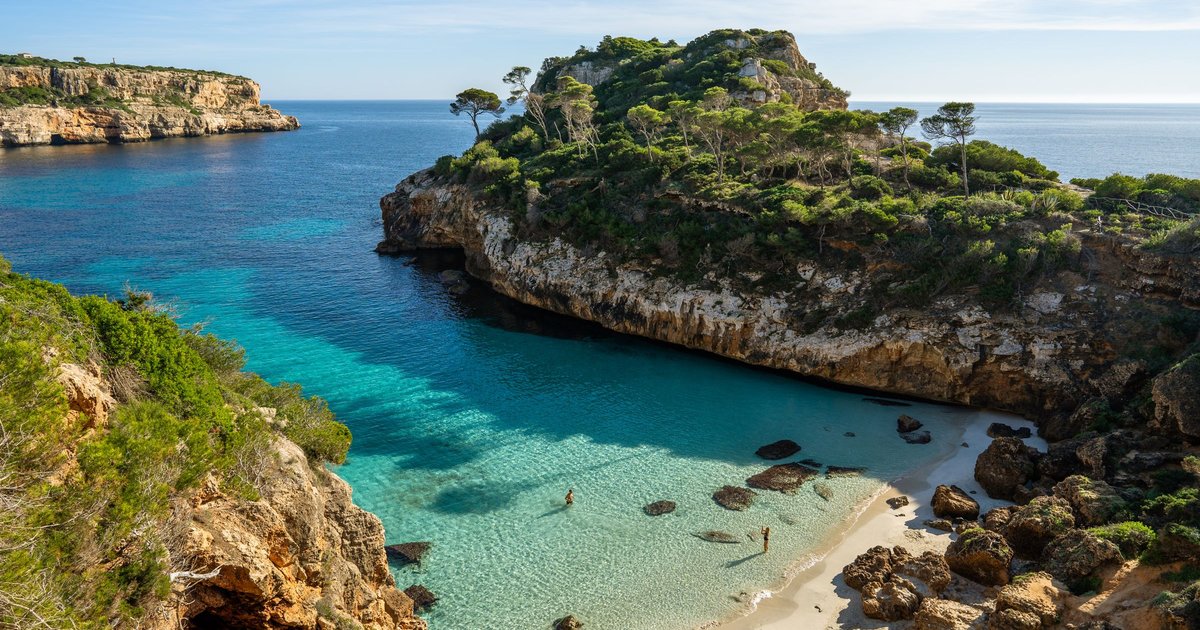 Rocky cove with turquoise water and pine-covered cliffs in Majorca, Spain