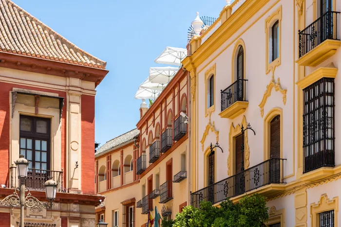 Charming traditional architecture with orange trees on a sunlit street in Seville, Spain