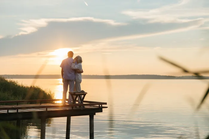 Retired couple watching the sunset from a wooden jetty in Spain